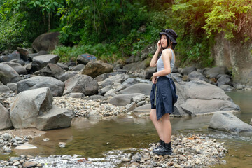Asian Woman Standing on River Rocks Enjoying Nature in Forest During Outdoor Adventure