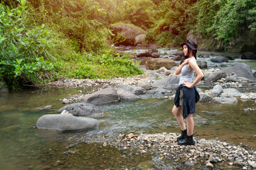 Asian Woman Standing on River Rocks Enjoying Nature in Forest During Outdoor Adventure