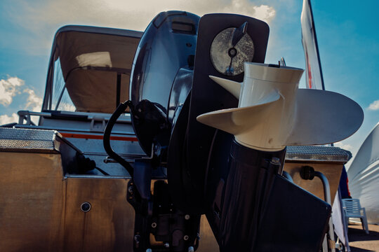 Fototapeta Close-up View of Boat Motor with Propeller Reflecting Blue Sky and Clouds on the Water