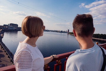 Fototapeta premium Couple on a Bridge Enjoying the View of the River and Cityscape on a Sunny Day