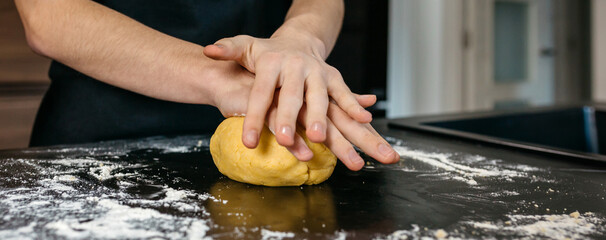 Close up of unrecognizable chef kneading dough on floured kitchen counter preparing homemade pasta