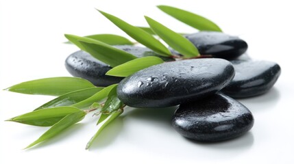 Fototapeta premium Black stones and green leaves are arranged on a white surface.