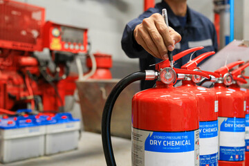Technicians check the pressure level of fire extinguishers in the fire control room for safety and...