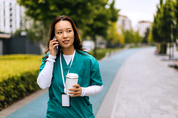 Nurse talking on the phone while walking along a city sidewalk on a sunny day