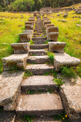 Stone stairs leading up a green hill to the ruins of an ancient greek city in Turkey