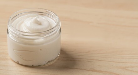 Moisturizing cream in a glass jar on a wooden surface  
