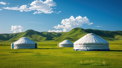 Yurts surrounded by lush green fields under a blue sky with fluffy clouds in a serene landscape