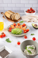 Healthy breakfast with avocado, salmon, whole grain bread and cherry tomatoes on a light tiled background. Balanced nutrition. Concept of natural breakfast and healthy lifestyle