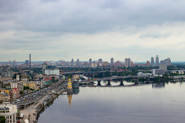Obraz premium Panoramic view from the Glass Bridge overlooking the Church on the Water, boats on the Dnieper River, and the historic Podil district in Kyiv, Ukraine.