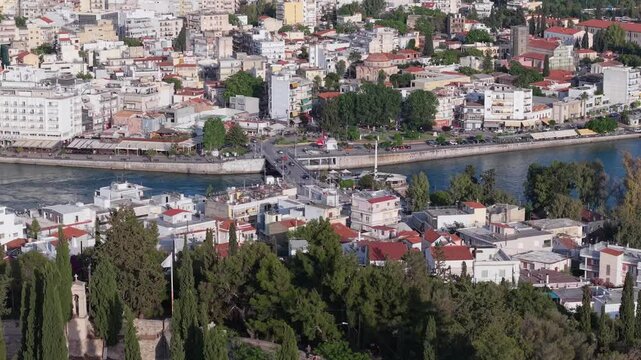 A cinematic drone reveal of Chalkida&rsquo;s old bridge, unfolding the view toward Kanithos hill with its castle ruins and the chapel of Prophet Elias above the city