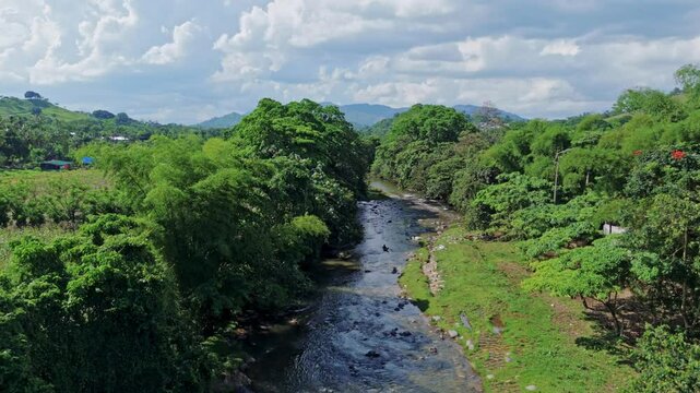 Aerial flyover of R&iacute;o Maim&oacute;n winding through lush valley, farmland and surrounding mountains in Puerto Plata, Dominican Republic
