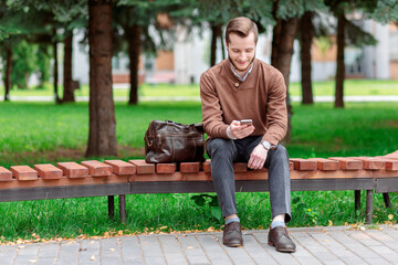 Fototapeta premium Happy bearded man with phone sitting on bench in park