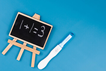 Positive pregnancy test, gynecological ultrasound image, and chalkboard with "1+1=3" written on it. pregnancy, family planning, parenthood, prenatal care and the joy of expecting a baby concept.