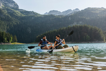 Couple kayaking in beautiful mountain lake on sunny day