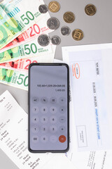 Israel currency New Israeli shekel (NIS) banknotes and agorot coins, with calculator and bills for electricity, water, and taxes, concept of inflation crisis, rising prices, and financial management.