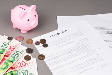 Rental or Residential Lease agreement contract in Hebrew and piggy bank. Short and long term rentals in Israel, housing searching crisis, signing lease agreement, and rising prices.