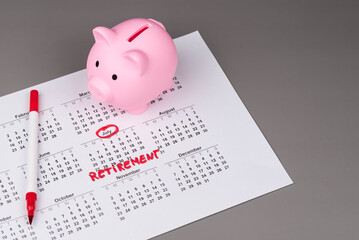Piggy bank and calendar with the word 'Retirement' written on it, as savings for retirement and planning. Concept of early retirement, the Financial Independence, Retire Early movement (FIRE).