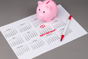 Piggy bank and calendar with the word 'Retirement' written on it, as savings for retirement and planning. Concept of early retirement, the Financial Independence, Retire Early movement (FIRE).