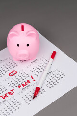 Piggy bank on calendar with the words 'Debt Free' written on it, symbolizing saving money, financial freedom, and achieving a debt-free lifestyle. Concept of financial independence and budgeting.