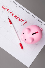 Piggy bank and calendar with the word 'Retirement' written on it, as savings for retirement and planning. Concept of early retirement, the Financial Independence, Retire Early movement (FIRE).