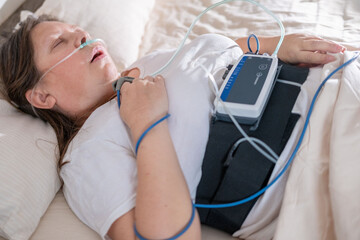 Woman wearing portable sleep tracker on abdomen, Female patient with sleep and health monitoring...