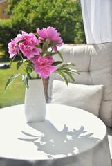 Peonies in a vase on a table on the terrace.