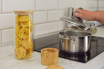 A woman opens the lid of a pot of boiling water to cook pasta
