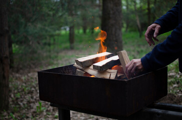 Lighting firewood in the grill. A burner in hand, flames.