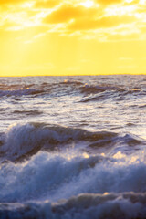 A breathtakingly serene view of the gentle ocean waves as they crash softly beneath a warm, golden sunset sky