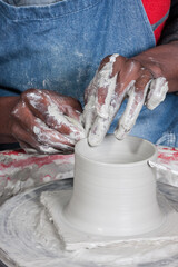 textured strong wet hands immersed in and working with items of pottery moulding clay showing close up detail