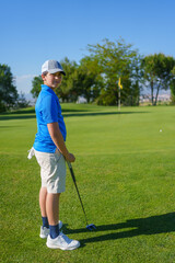 Young golfer putting on the green on a sunny day
