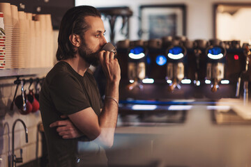 Man enjoys a quiet moment sipping coffee in a cozy cafe during the morning in an urban setting