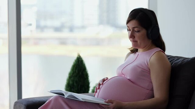 Expectant mother reads with headphones on near window light