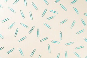 Flat lay of blue paper clips on yellow background