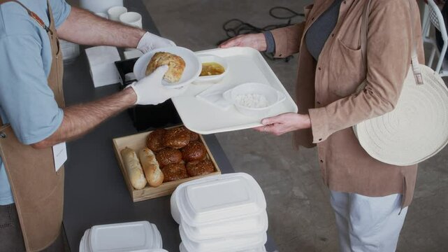 View from above of people in need receiving hot meals from volunteers at food service counter
