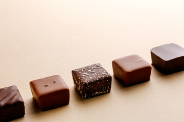 Minimal overhead shot of chocolate squares on beige background, elegant candy dessert composition
