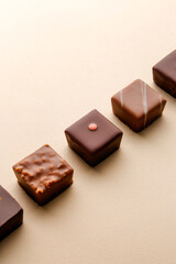 Minimal overhead shot of chocolate squares on beige background, elegant candy dessert composition