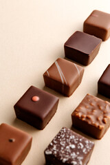 Minimal overhead shot of chocolate squares on beige background, elegant candy dessert composition