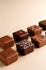 Minimal overhead shot of chocolate squares on beige background, elegant candy dessert composition