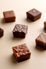 Minimal overhead shot of chocolate squares on beige background, elegant candy dessert composition