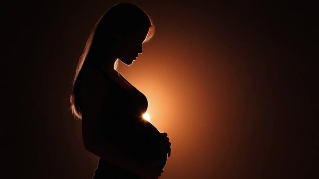 Celebrating pregnancy at dusk with a silhouette of a mother cradling her baby bump