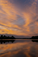 Reflective surface beautiful orange and pink sky background reflective look in large lake in Latvia near city Saldus, water sunset reflection on water surface