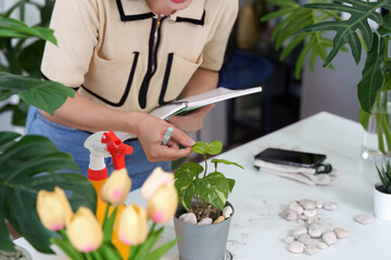 Plant Observation and Sustainability. A woman diligently inspects her green plants while...
