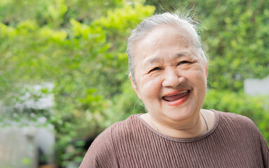 Cheerful older woman standing in the garden at home, smiling with perfect white teeth
