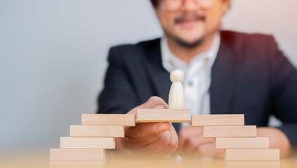 Happy businessman making a bridge of wooden blocks for people wooden icon to walk across