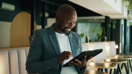 Mature businessman in suit smiling and using tablet in office during daytime - Powered by Adobe