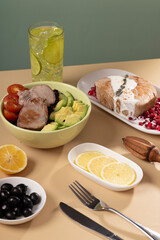 A bowl of delicious tuna and vegetable salad, lemonade, modern naturism on a coloured table, flat plan. Place for text