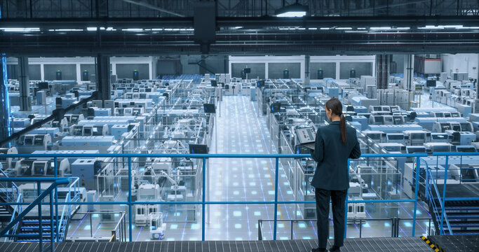 Factory Digitalization Visual Transformation: Female Engineer Uses Laptop to Activate Construction of Autonomous Robot Arm Industrial Facility. Industry Four Machinery Manufacturing of Products