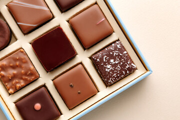 Minimal flatlay of open box with chocolate squares on beige background, elegant candy dessert packaging mockup concept