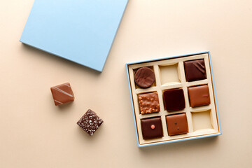 Minimal flatlay of open box with chocolate squares on beige background, elegant candy dessert packaging mockup concept